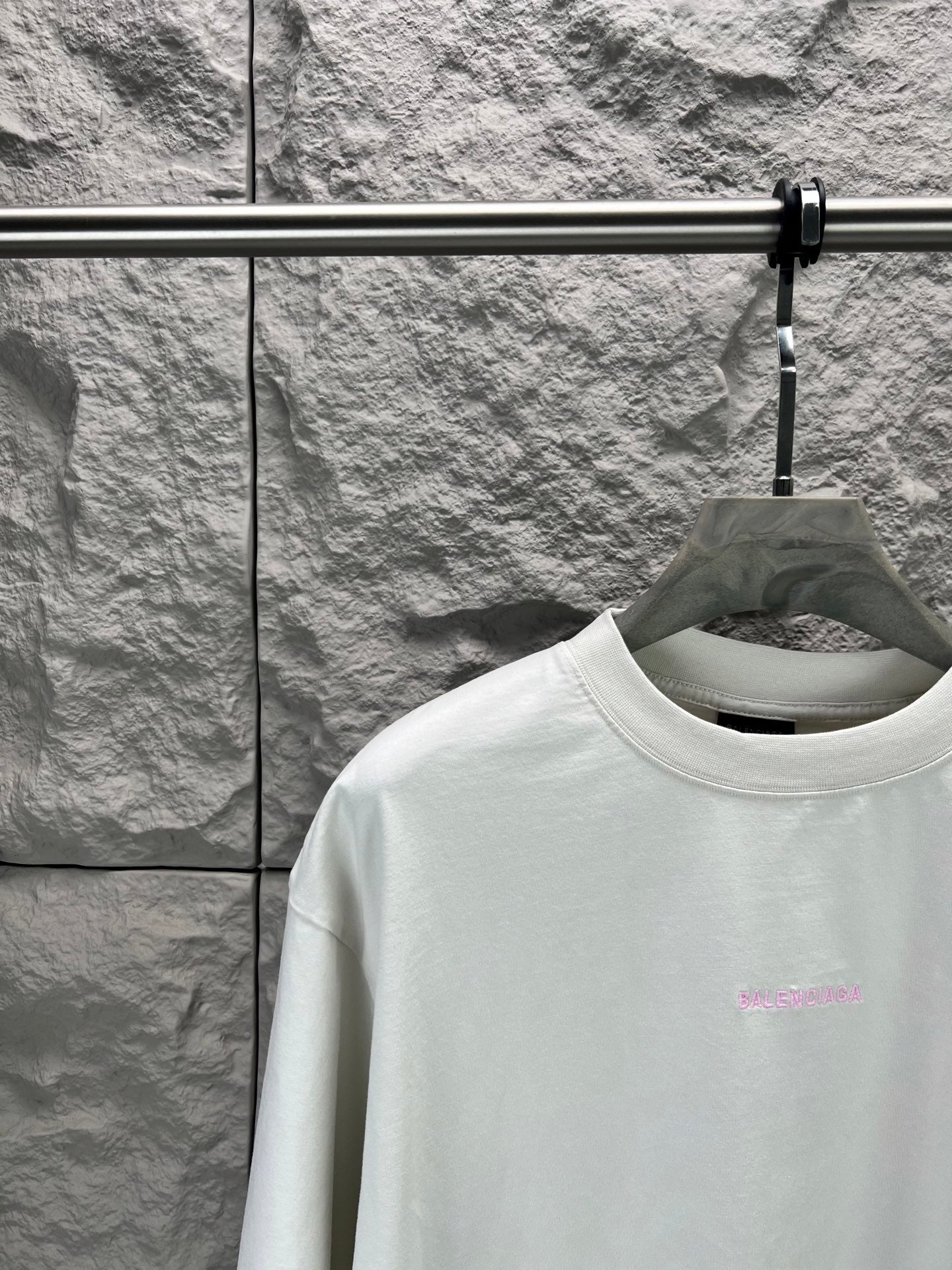 White T-shirt collar with small pink logo at left chest