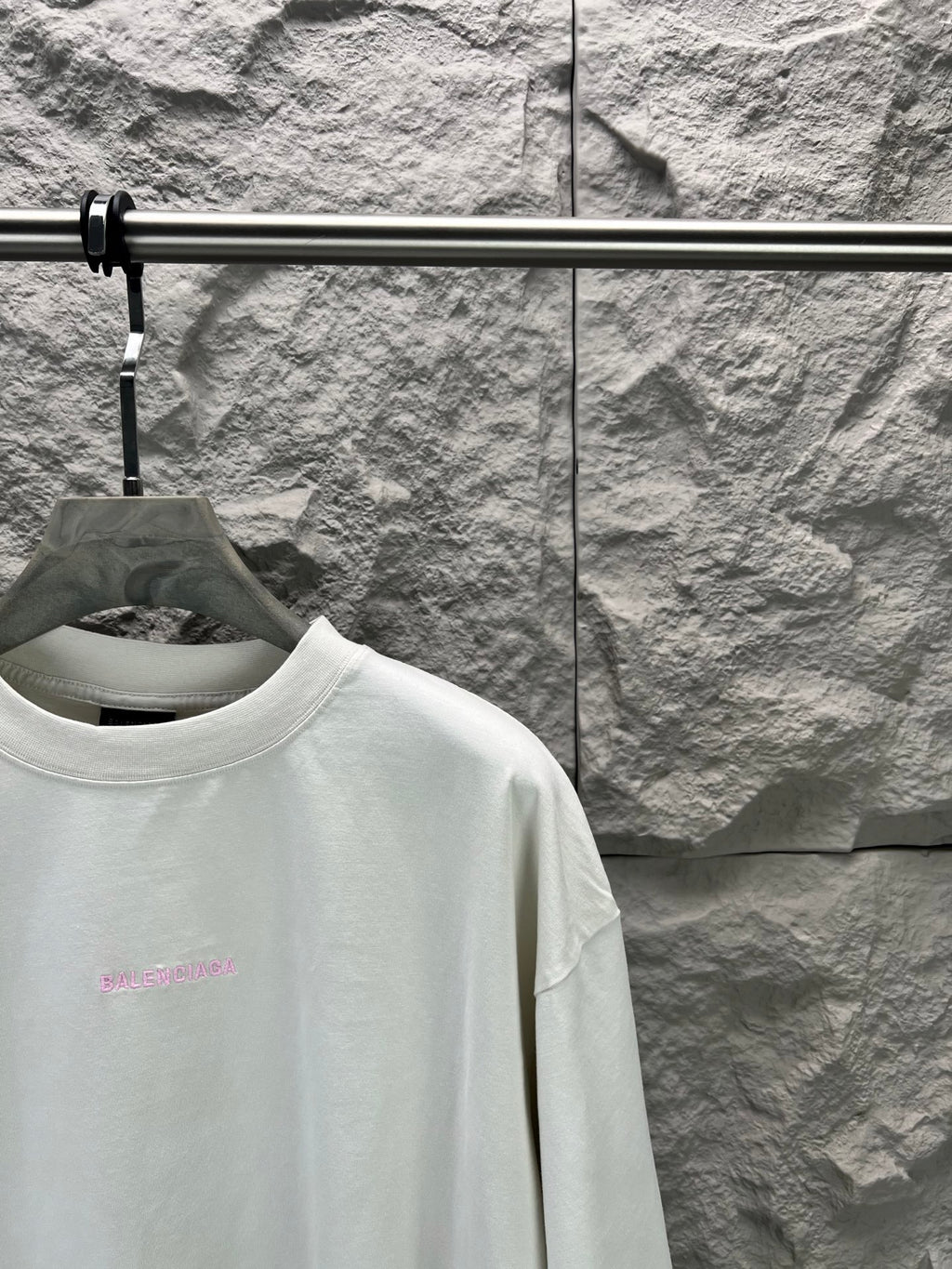 White T-shirt with small pink logo on chest, close-up