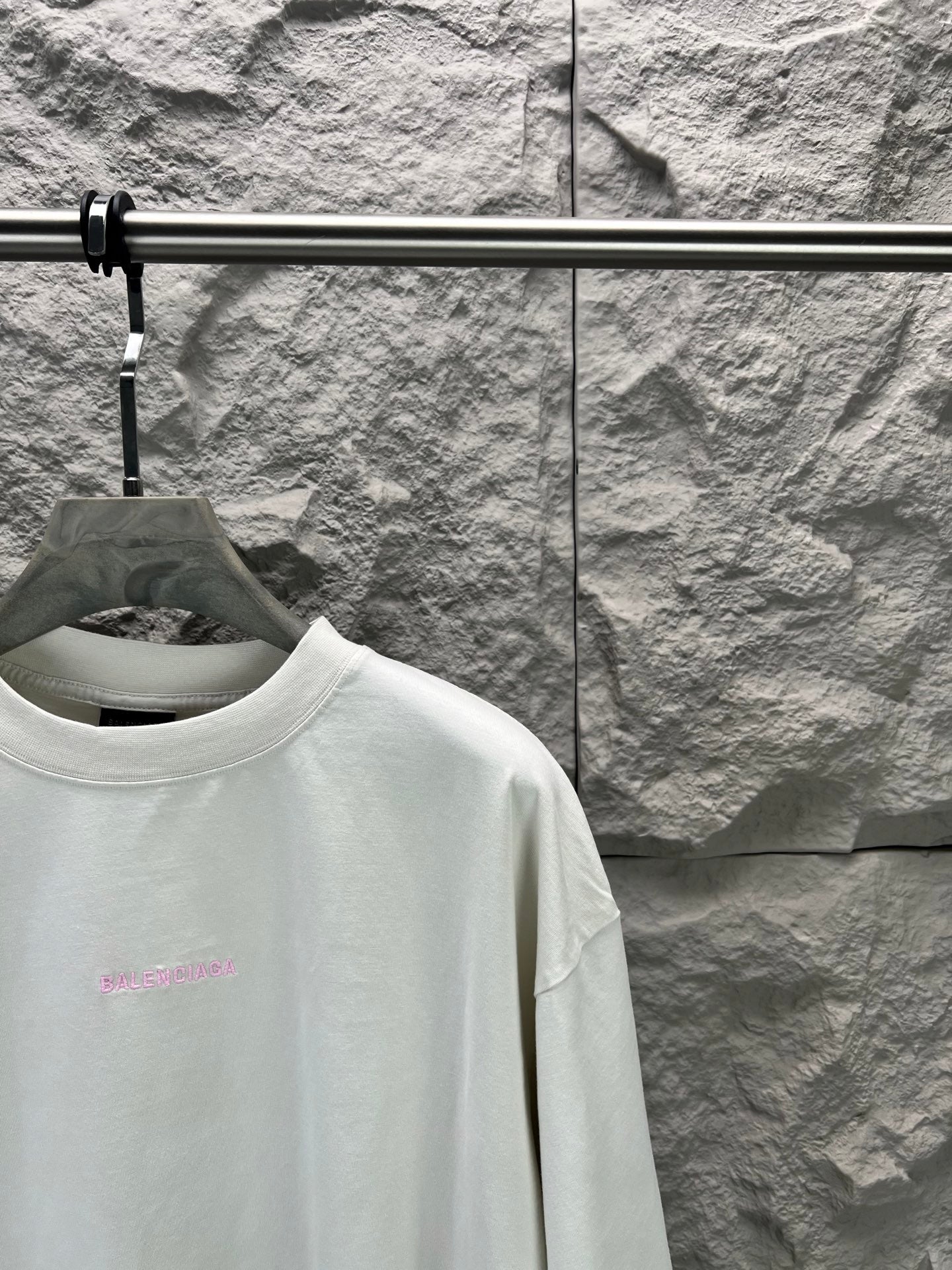 White T-shirt with small pink logo on chest, close-up