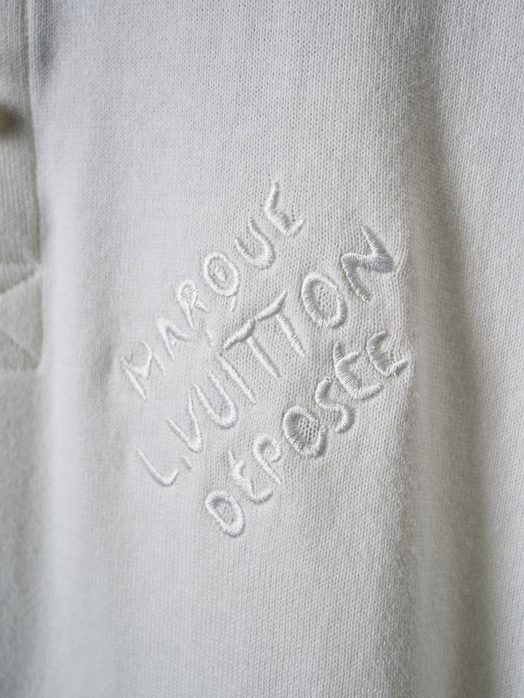 Louis Vuitton embossed script logo on white polo fabric