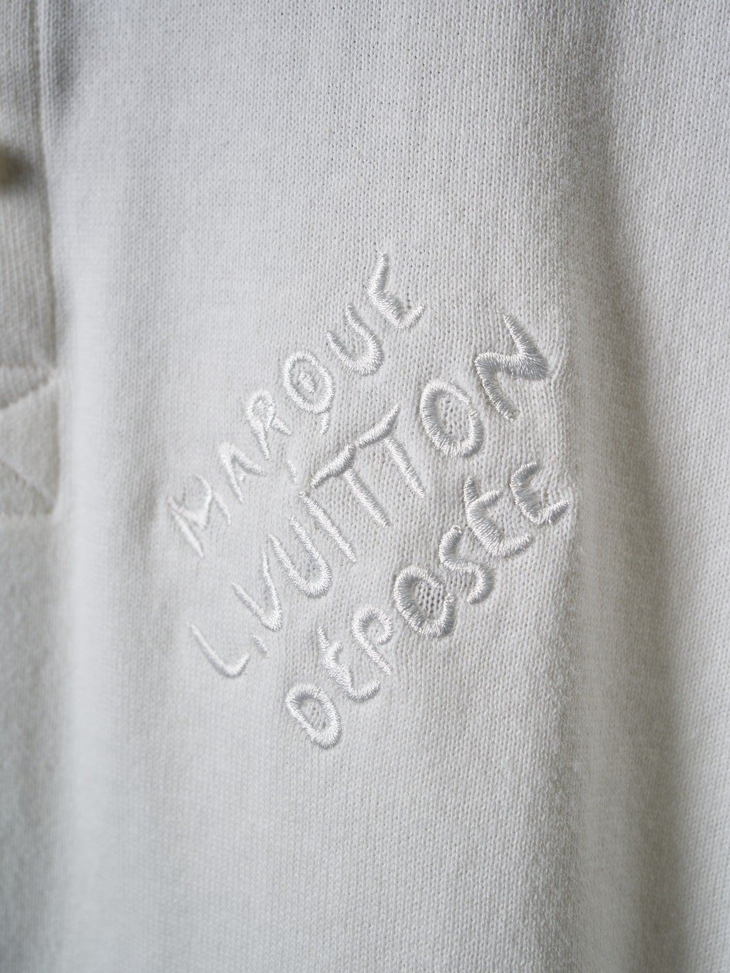 Louis Vuitton embossed script logo on white polo fabric