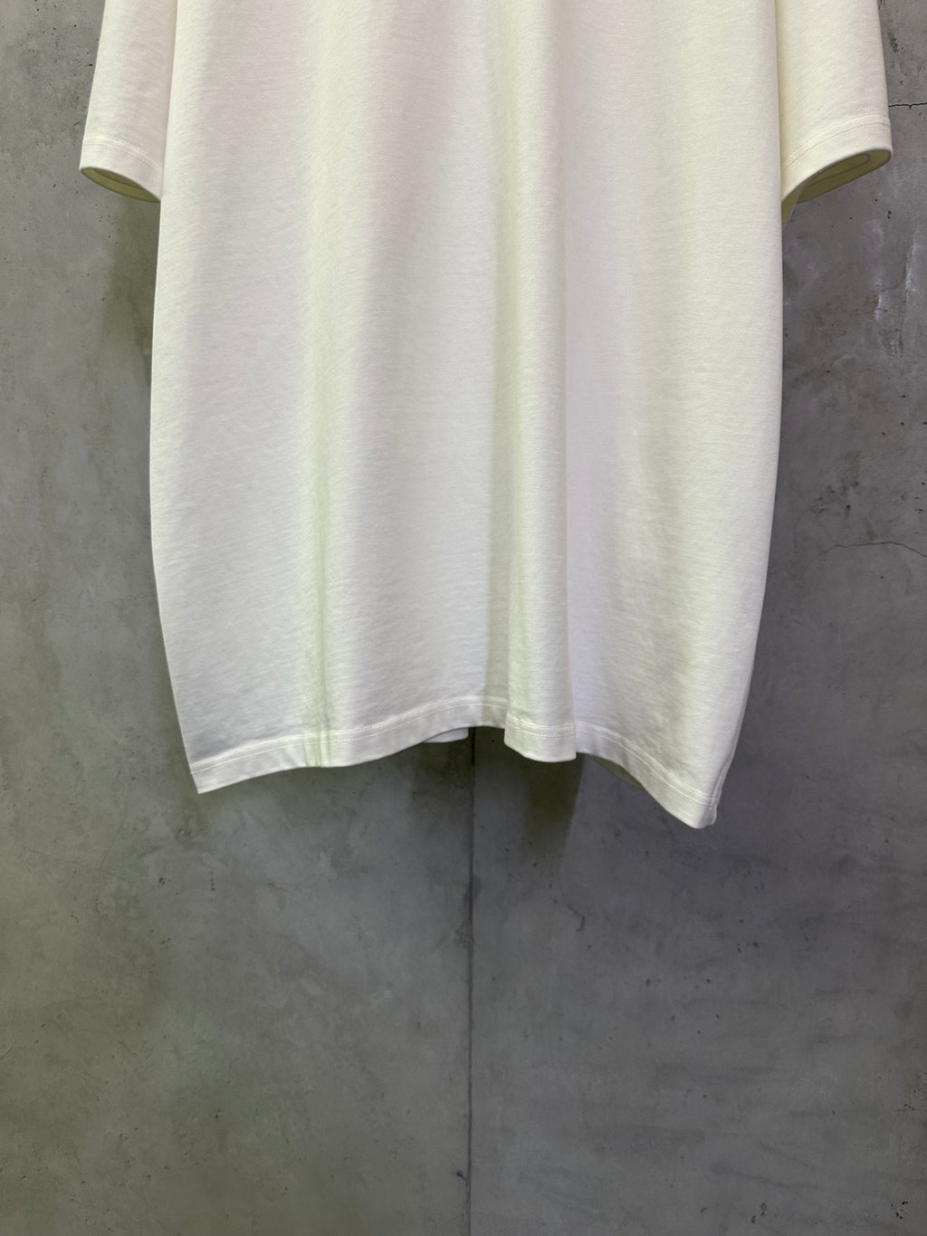 Off-white crewneck T-shirt with straight hem and short sleeves, laid flat for detail