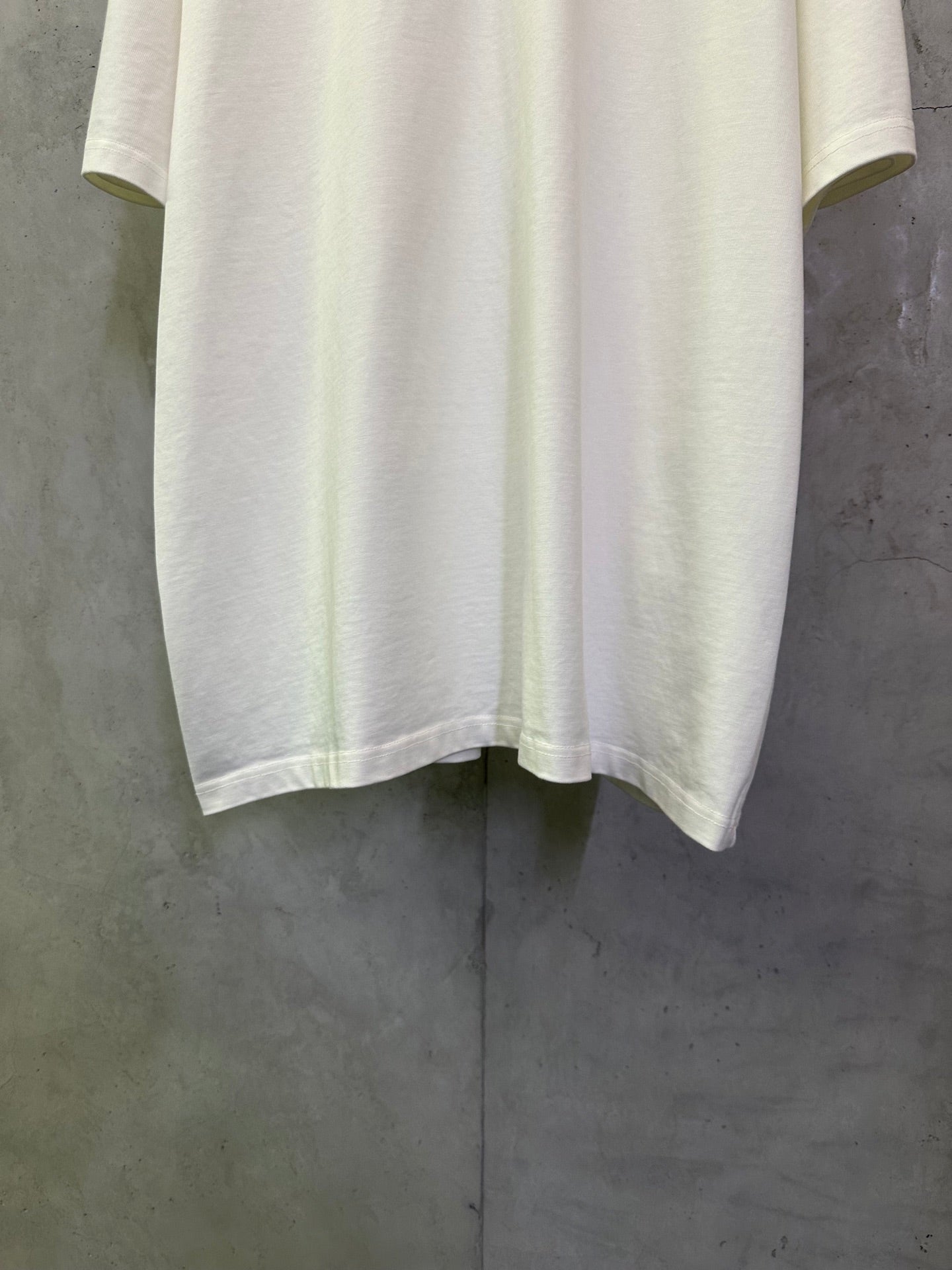 Off-white crewneck T-shirt with straight hem and short sleeves, laid flat for detail