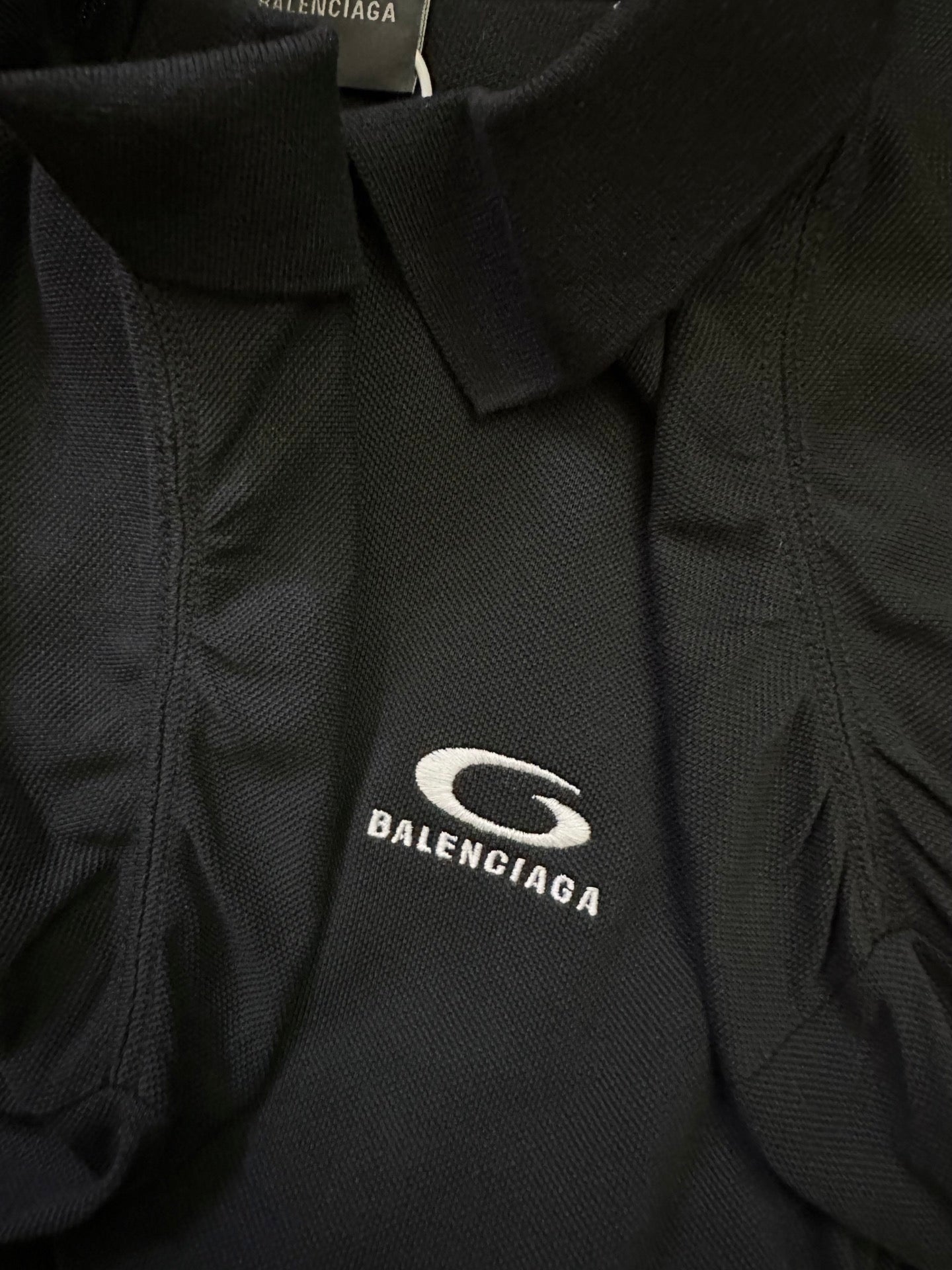 Balenciaga polo shirt fabric close-up with embroidered oval logo on chest