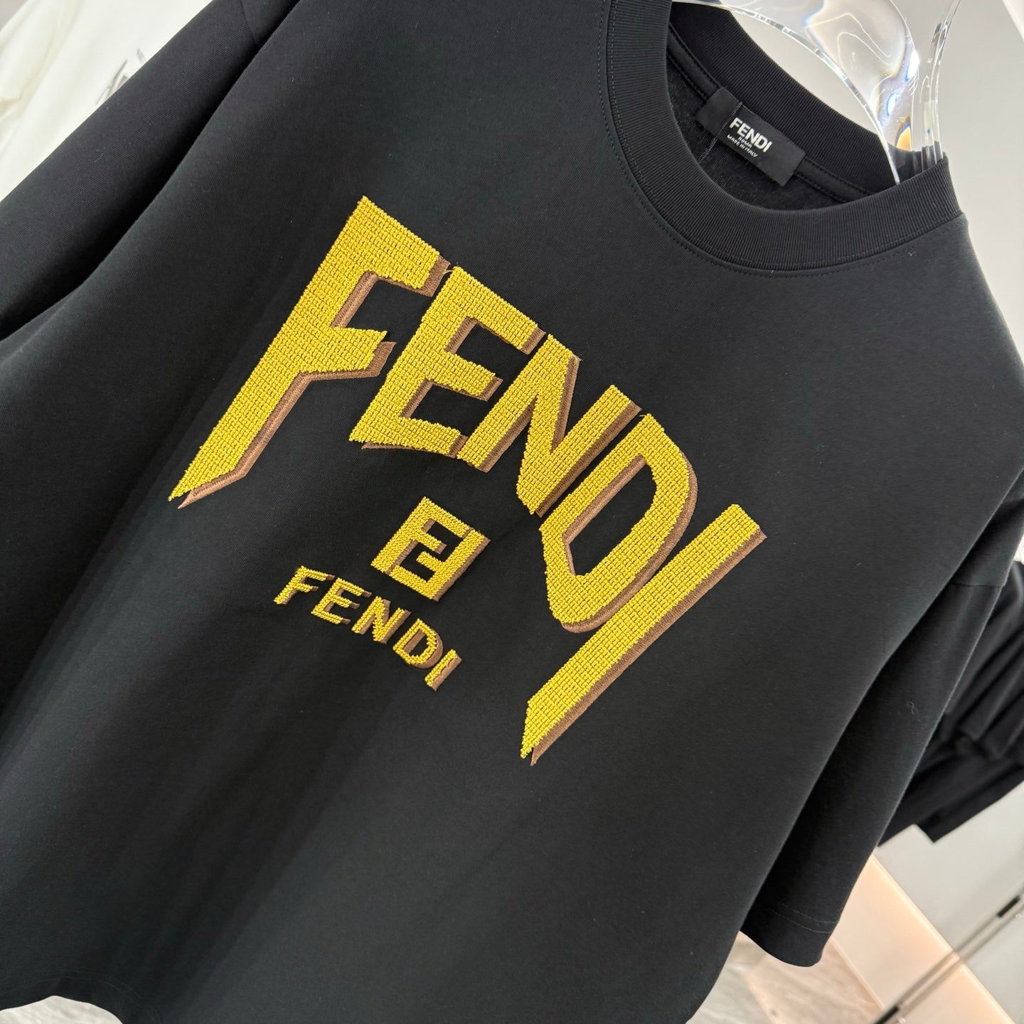 Black short-sleeve T-shirt with yellow FENDI lettering logo on the front