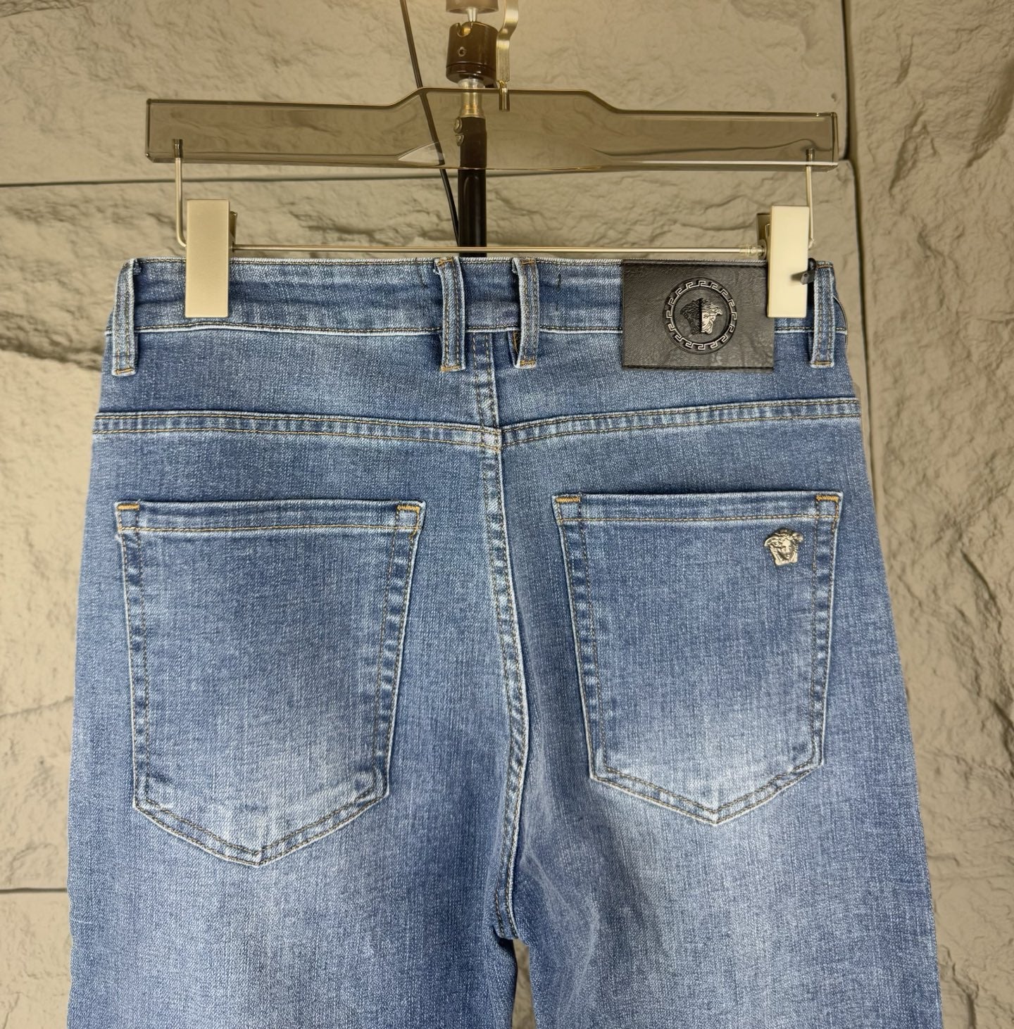 Versace blue denim jeans back view with stitched pockets and central waistband logo patch