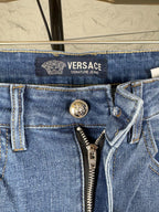 Versace denim jeans waistband close-up with VERSACE text logo and zipper fly