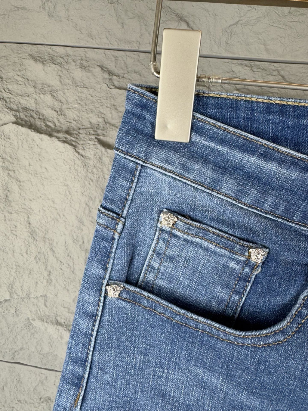 Versace blue denim jeans close-up of front pocket and coin logo patch on waistband