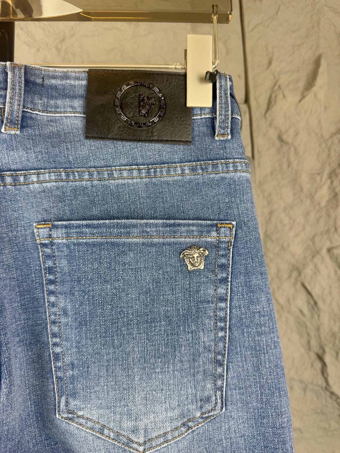 Versace blue denim jeans close-up of front pocket with small gold-toned emblem patch