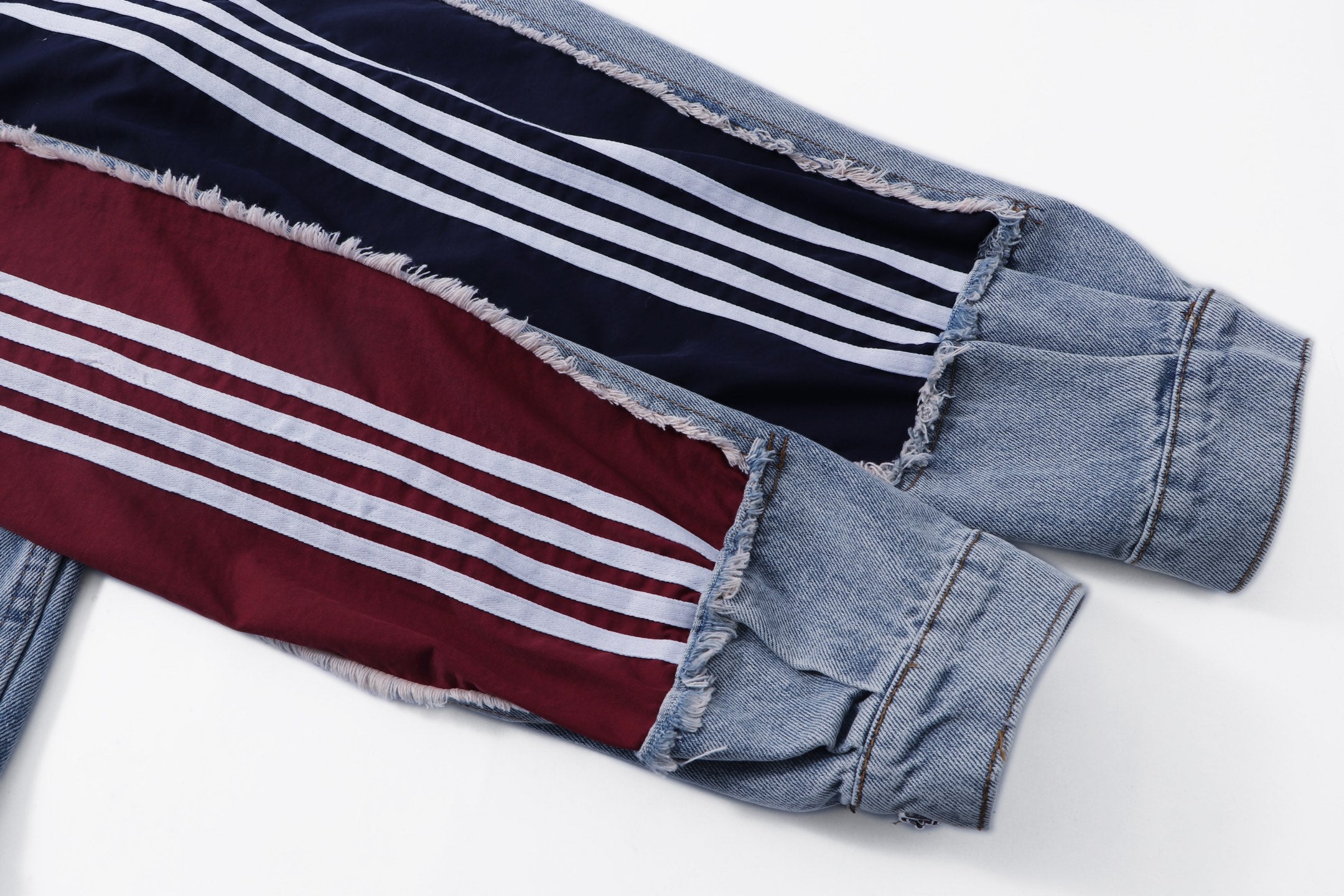 Denim jacket sleeve detail with maroon panel and white striped trim