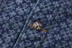 Decorative silver-toned button on dark blue patterned shirt