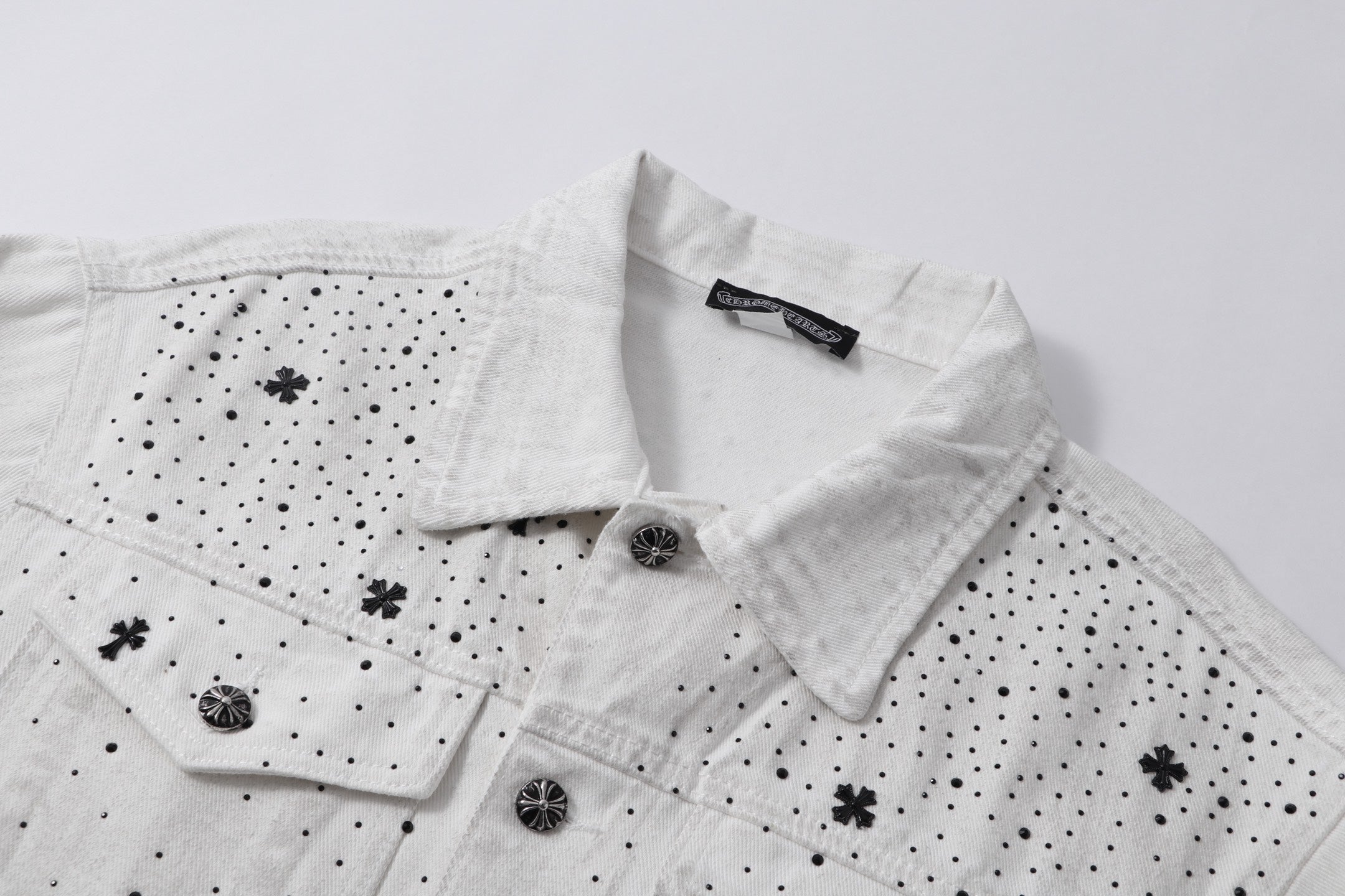 White denim jacket collar and button placket with embroidered cross and dot details