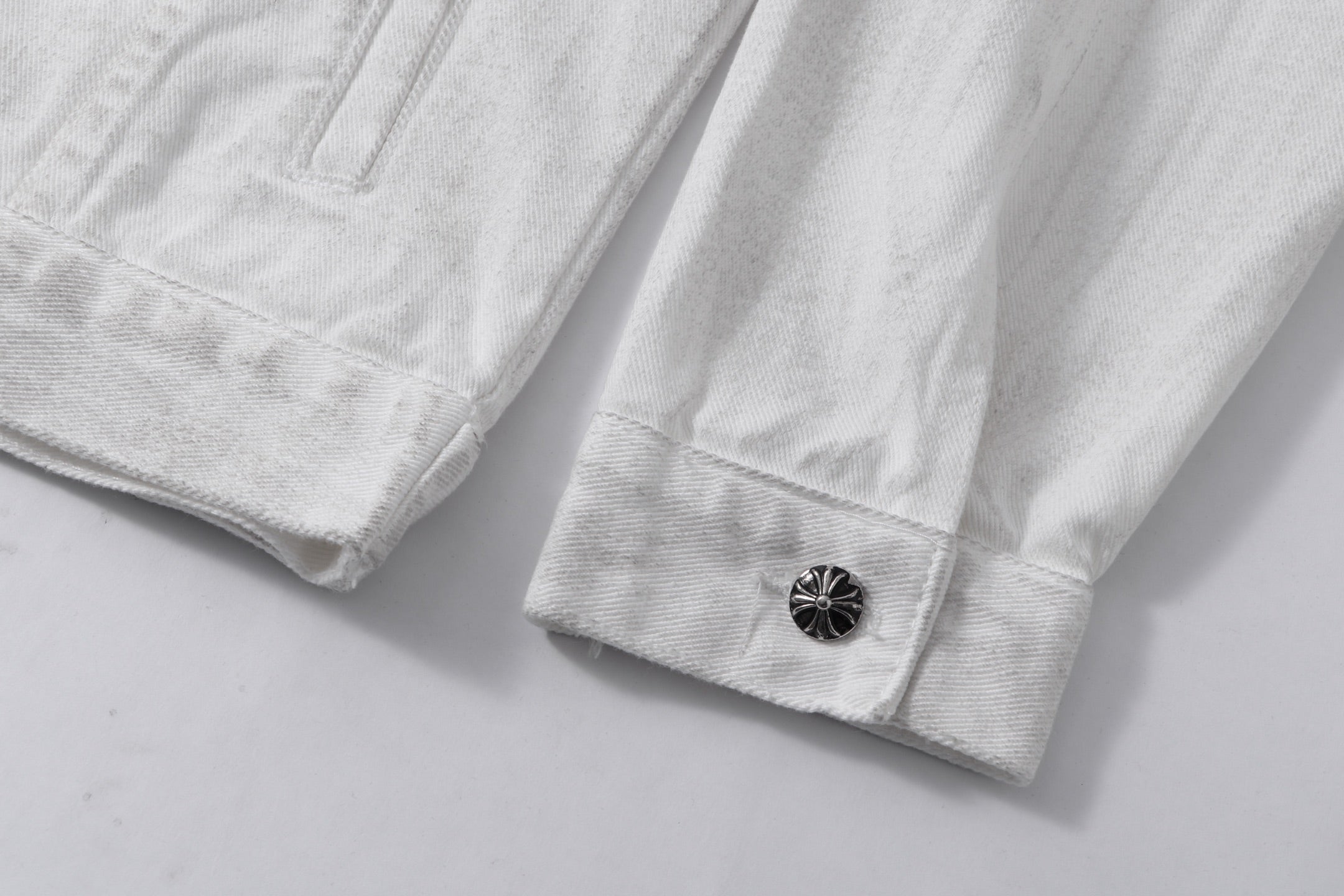 White denim jacket sleeve cuff with dark button closure