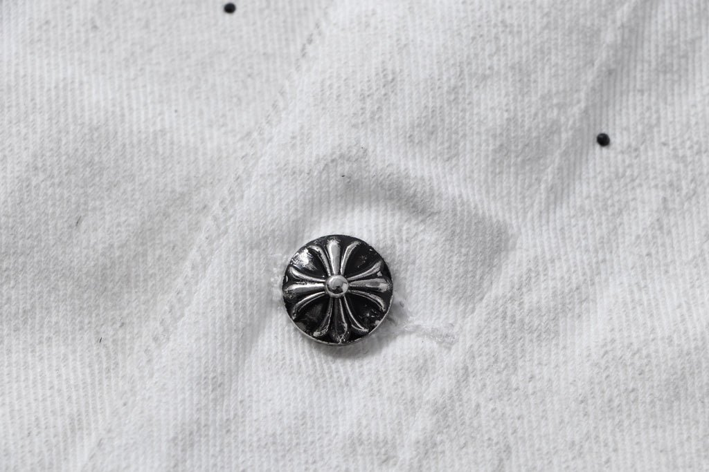 Dark metal button on white denim jacket with ridged floral design