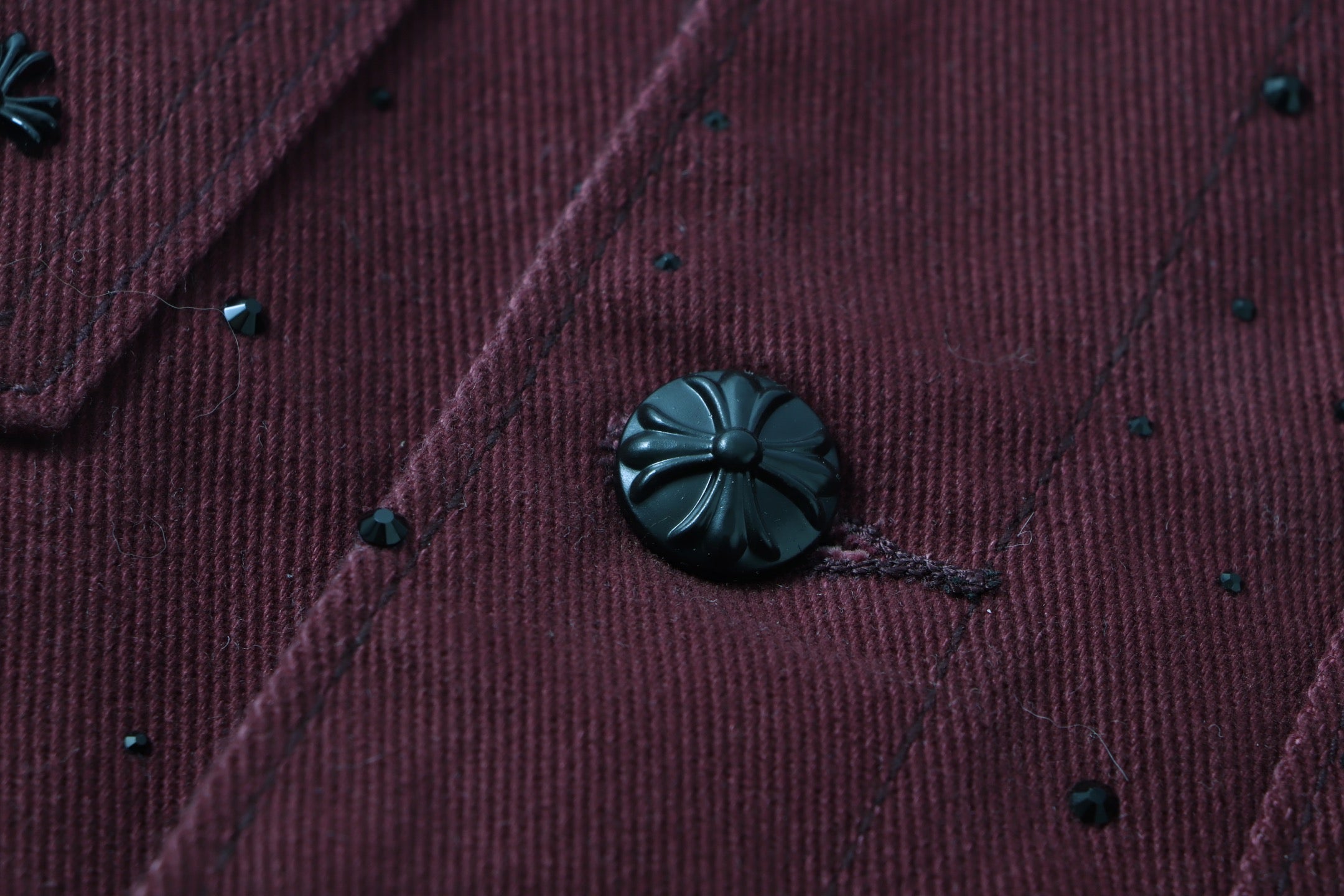 Long-sleeve jacket fabric detail with embroidered speckles and dark button