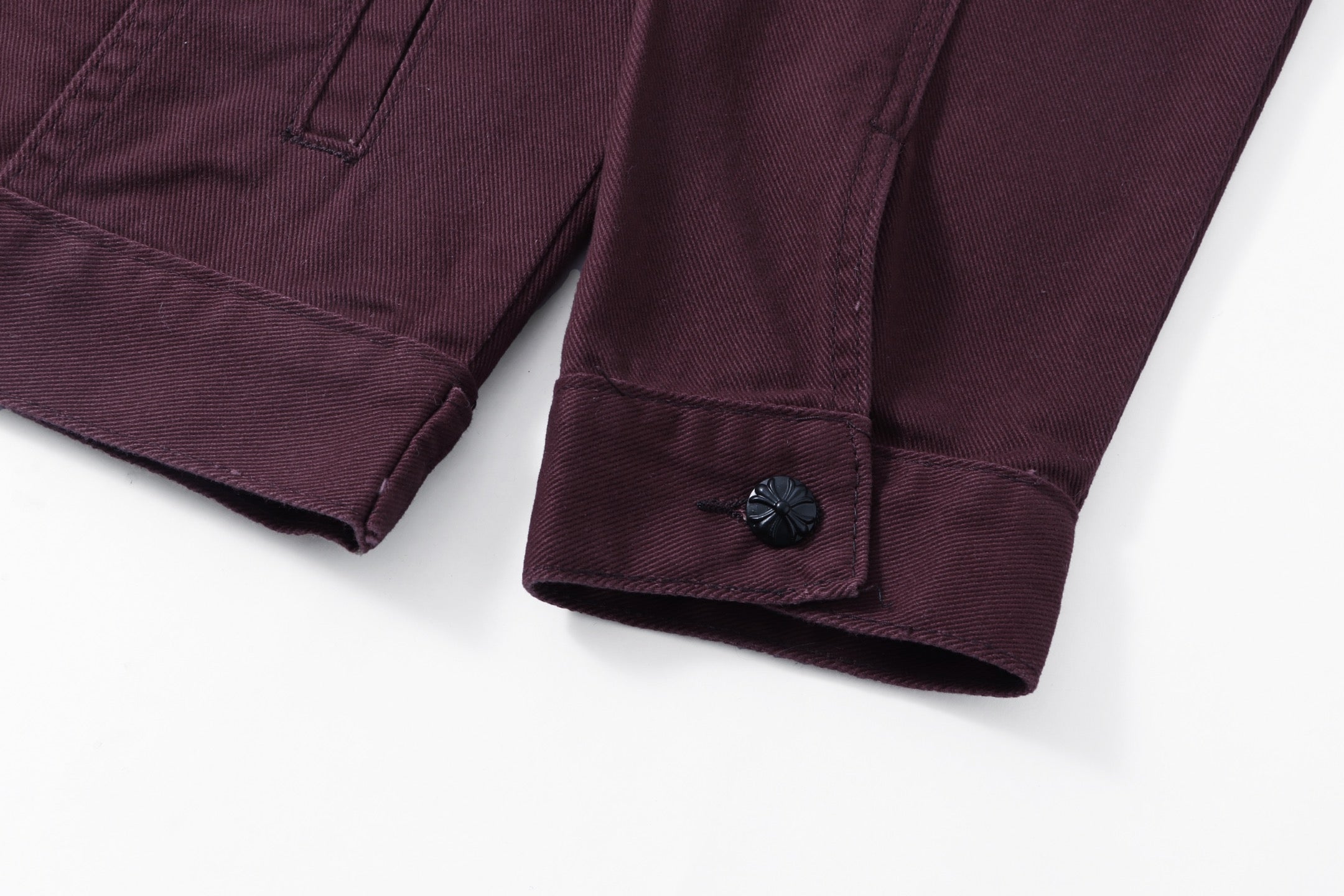 Sleeve cuff and button detail on dark plum long-sleeve jacket