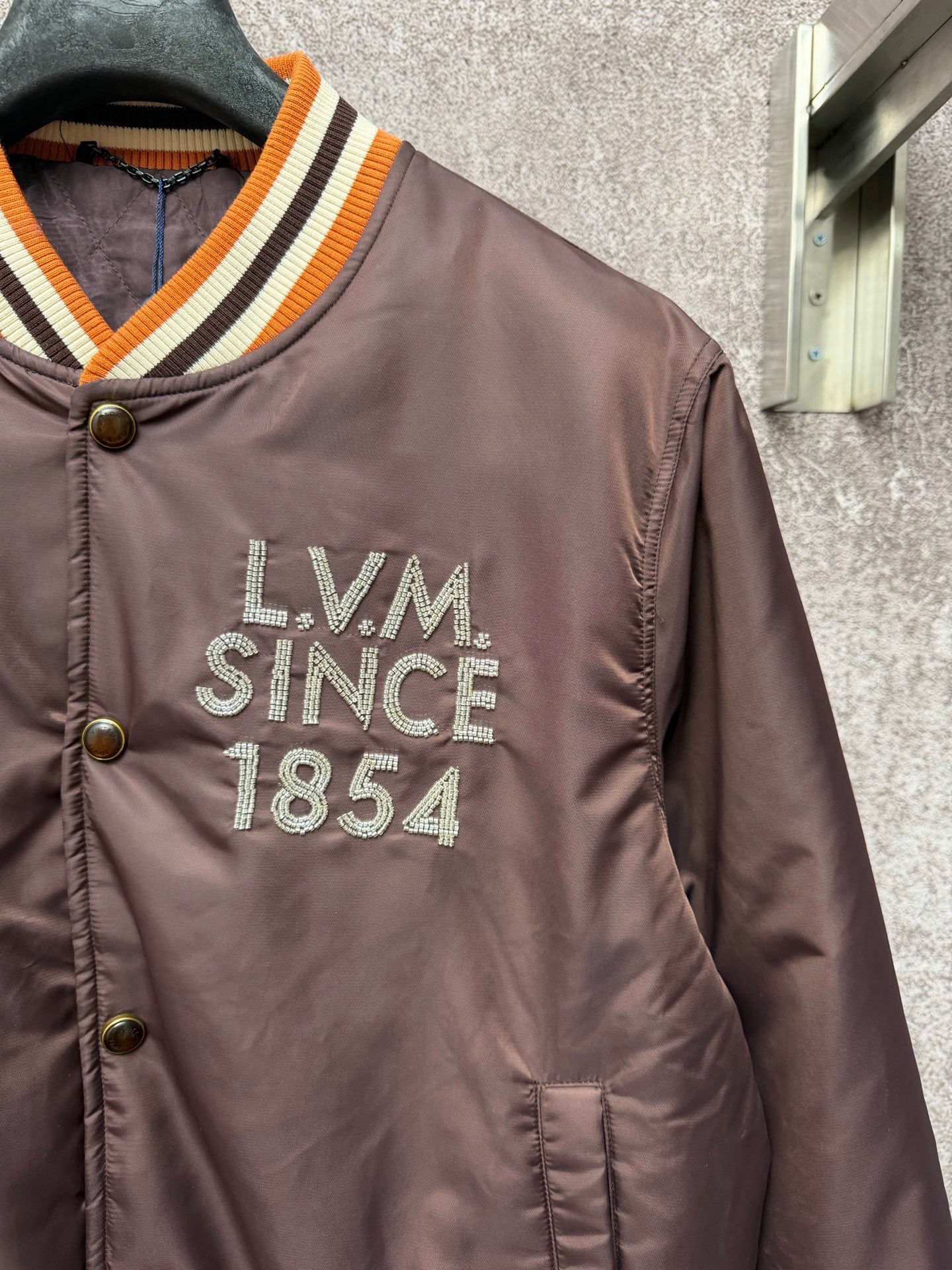 Louis Vuitton long bomber jacket close-up on chest logo reading LVM Since 1854