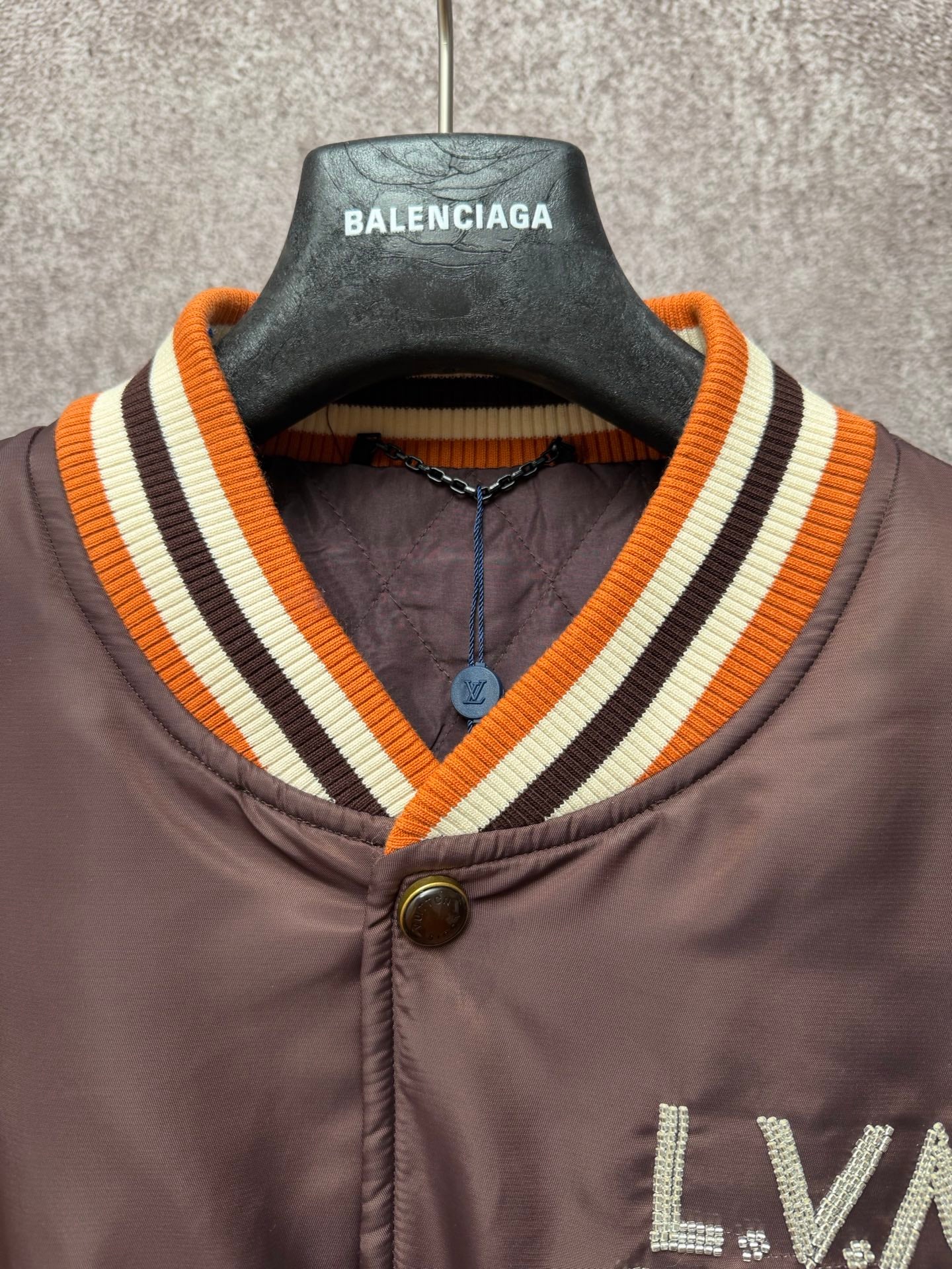 Louis Vuitton long bomber jacket neckline close-up with striped rib trim and metal snap