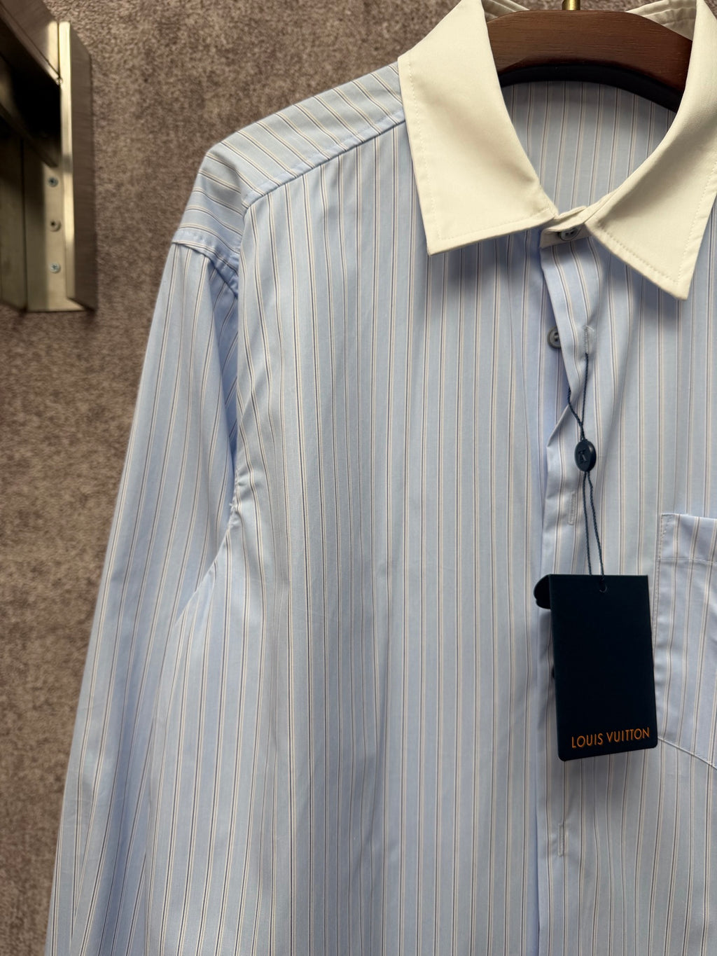 Light blue pinstripe shirt with cream collar and hanging black tag