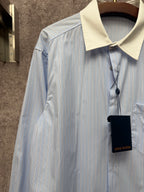 Light blue pinstripe shirt with cream collar and hanging black tag