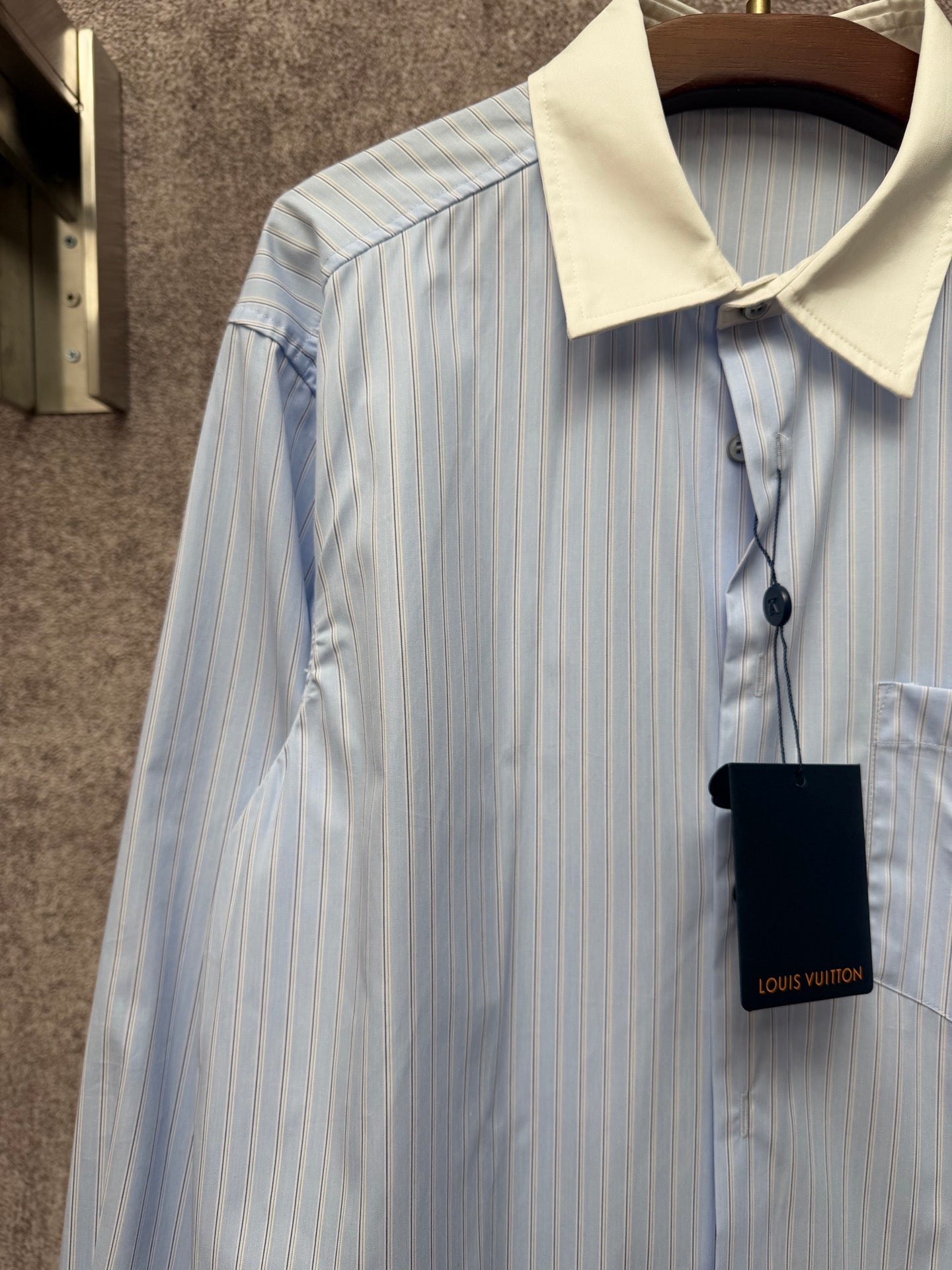 Light blue pinstripe shirt with cream collar and hanging black tag
