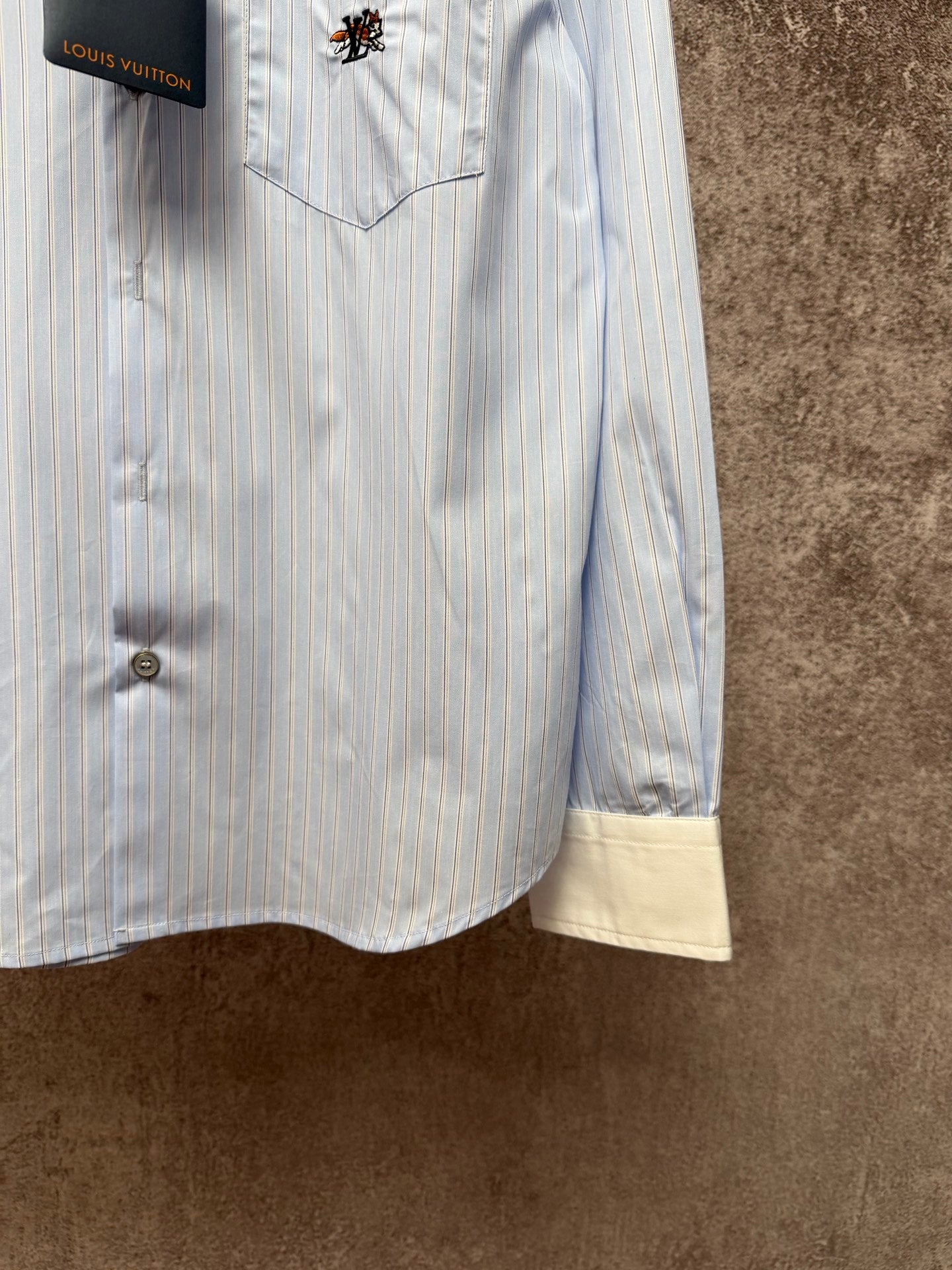 Light blue pinstripe button-up shirt with cream hem facing and front buttons