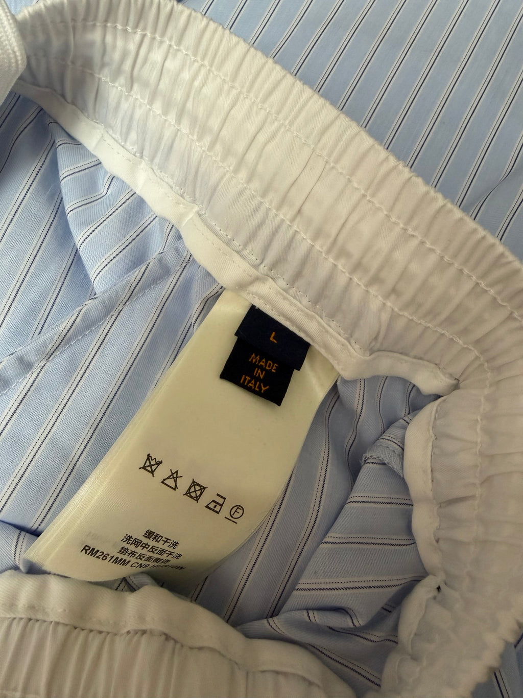 Inside view of light blue pinstripe shorts with woven brand label, Louis Vuitton