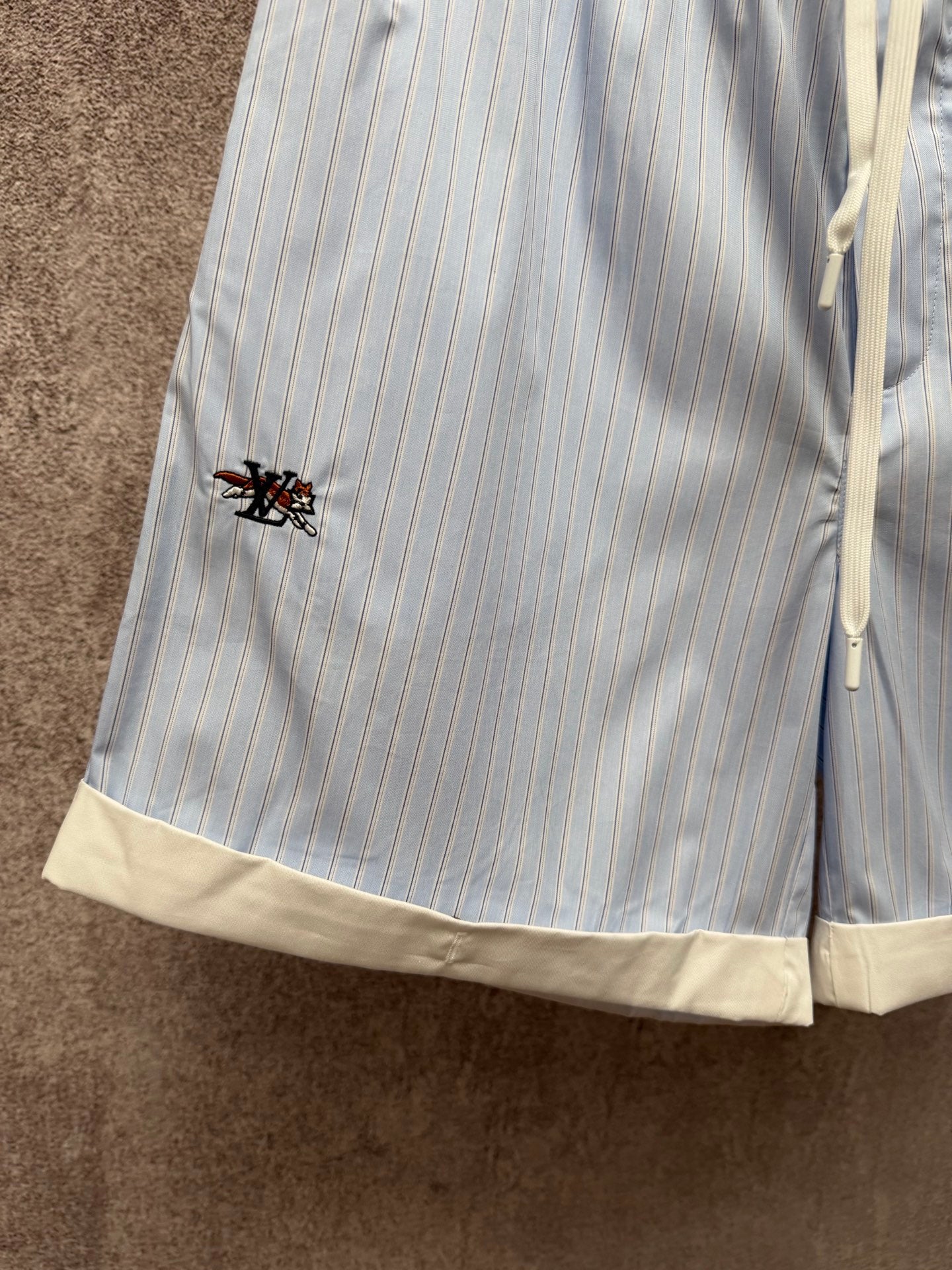 Light blue pinstripe shorts with cream hem trim and small logo on pocket, Louis Vuitton