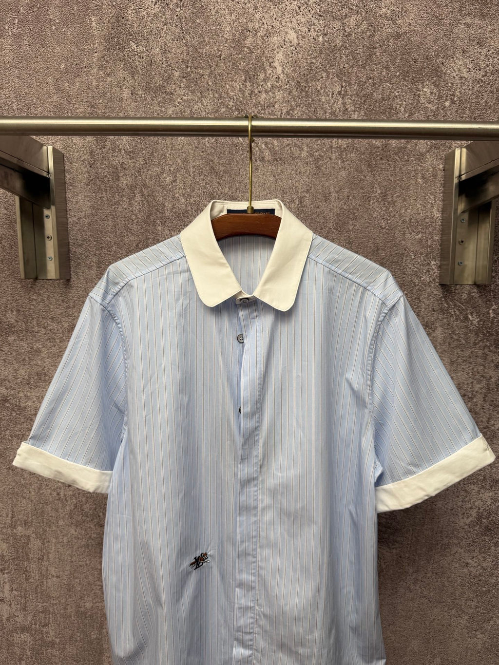 Light blue striped short-sleeve button shirt with cream collar and small chest emblem