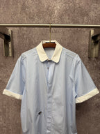 Light blue striped short-sleeve button shirt with cream collar and small chest emblem