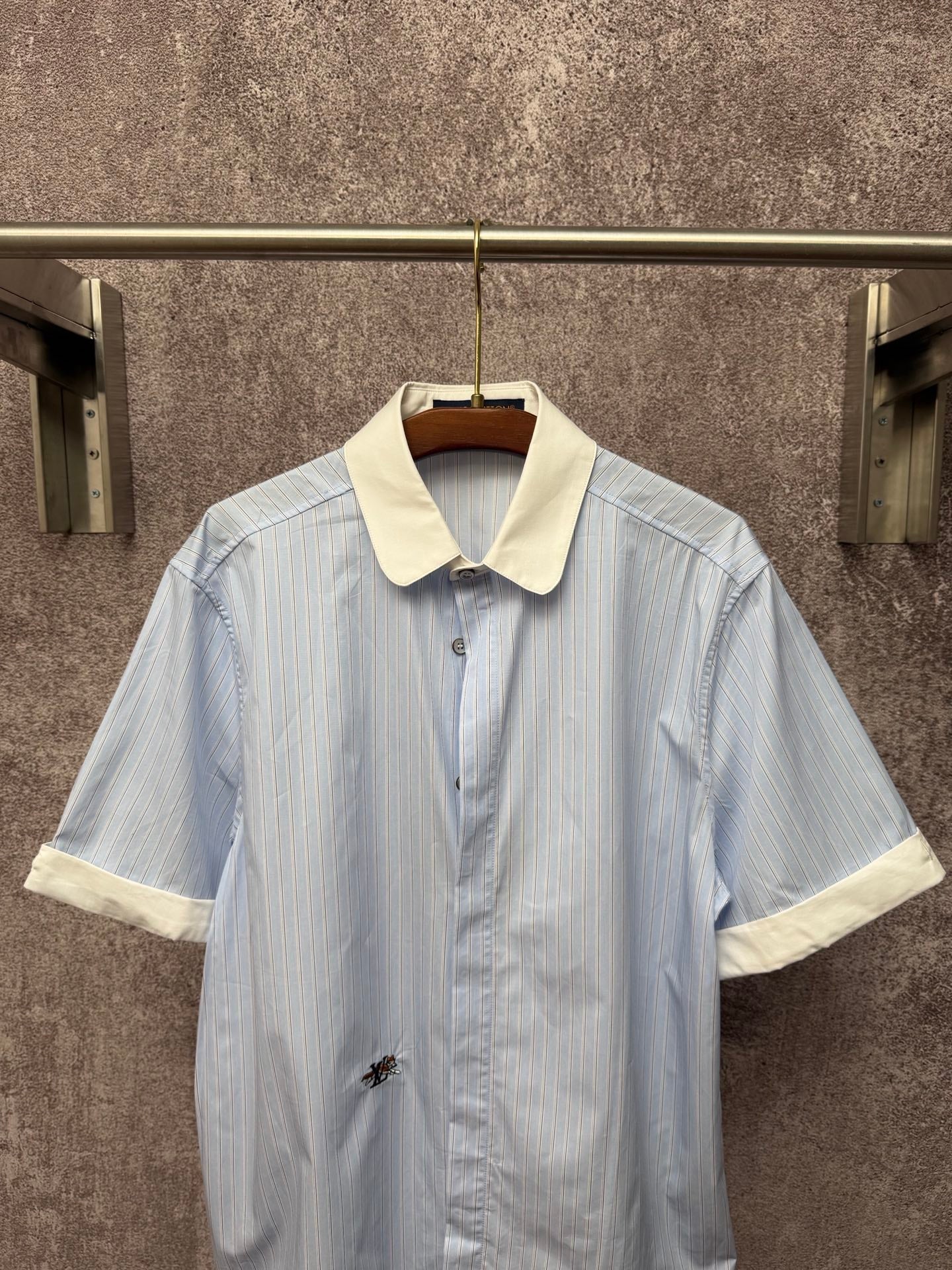 Light blue striped short-sleeve button shirt with cream collar and small chest emblem