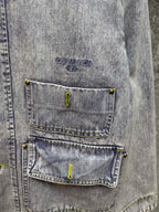 Close-up of light blue denim jacket chest pockets with yellow button accents
