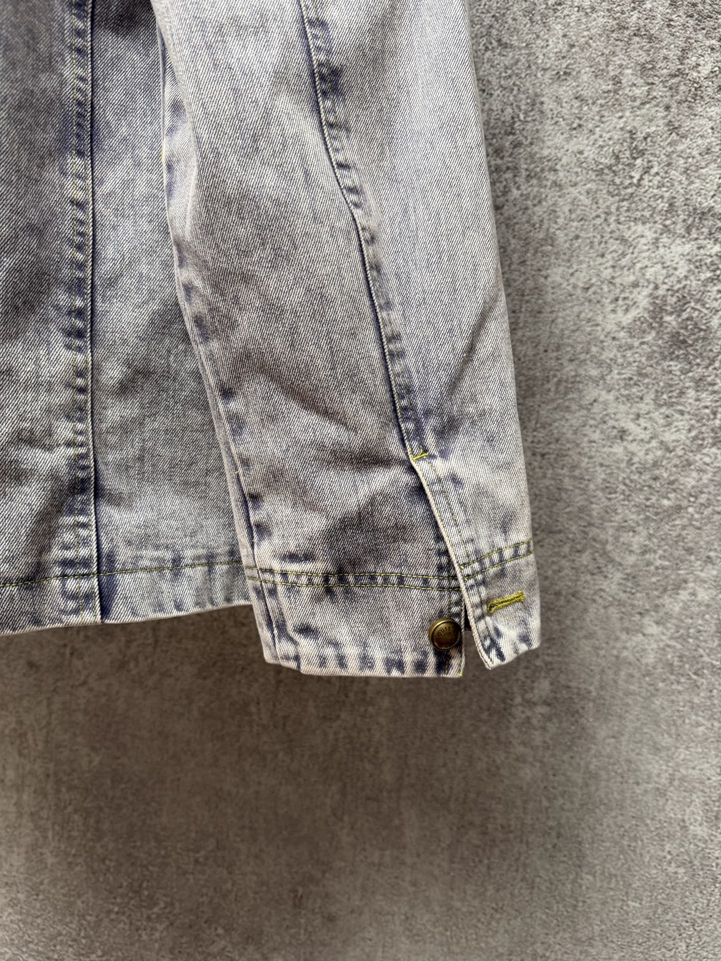Light blue denim jacket cuff with button and stitched hem