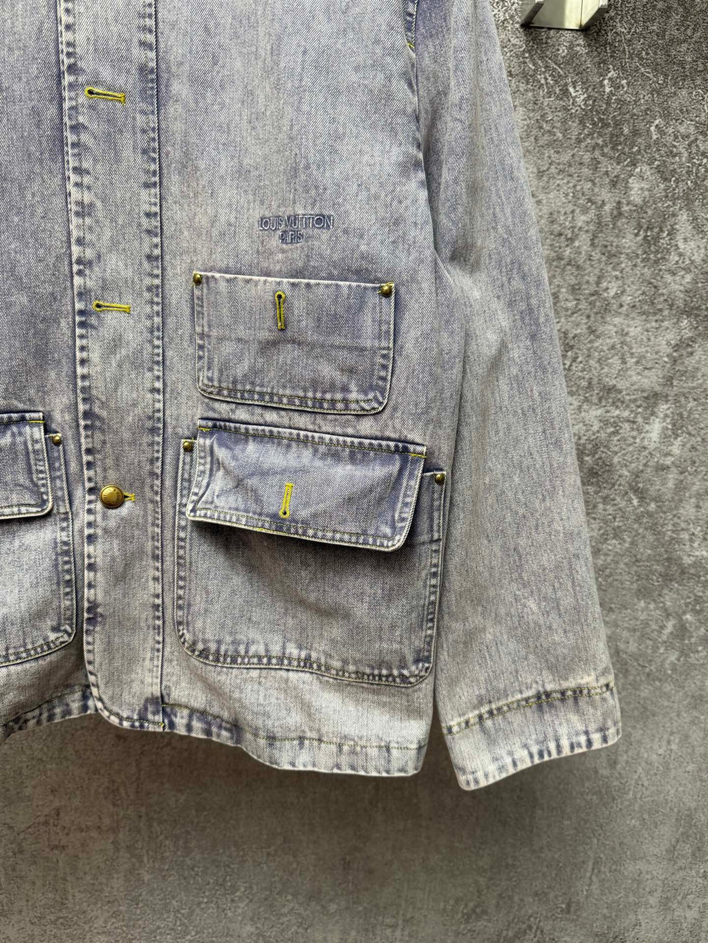 Light blue denim jacket side view with chest pockets and button details