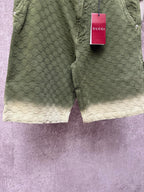 Green Gucci shorts back view with monogram pattern and red Gucci tag