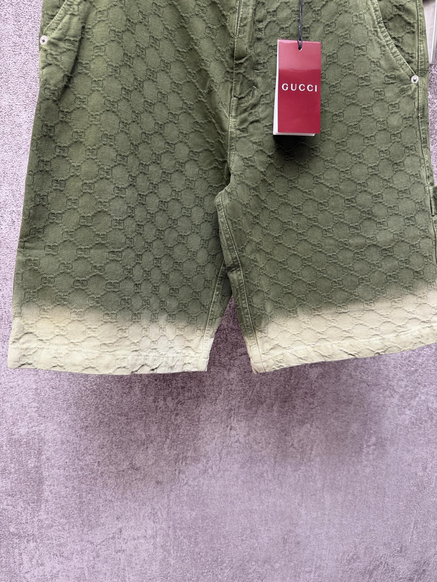 Green Gucci shorts back view with monogram pattern and red Gucci tag