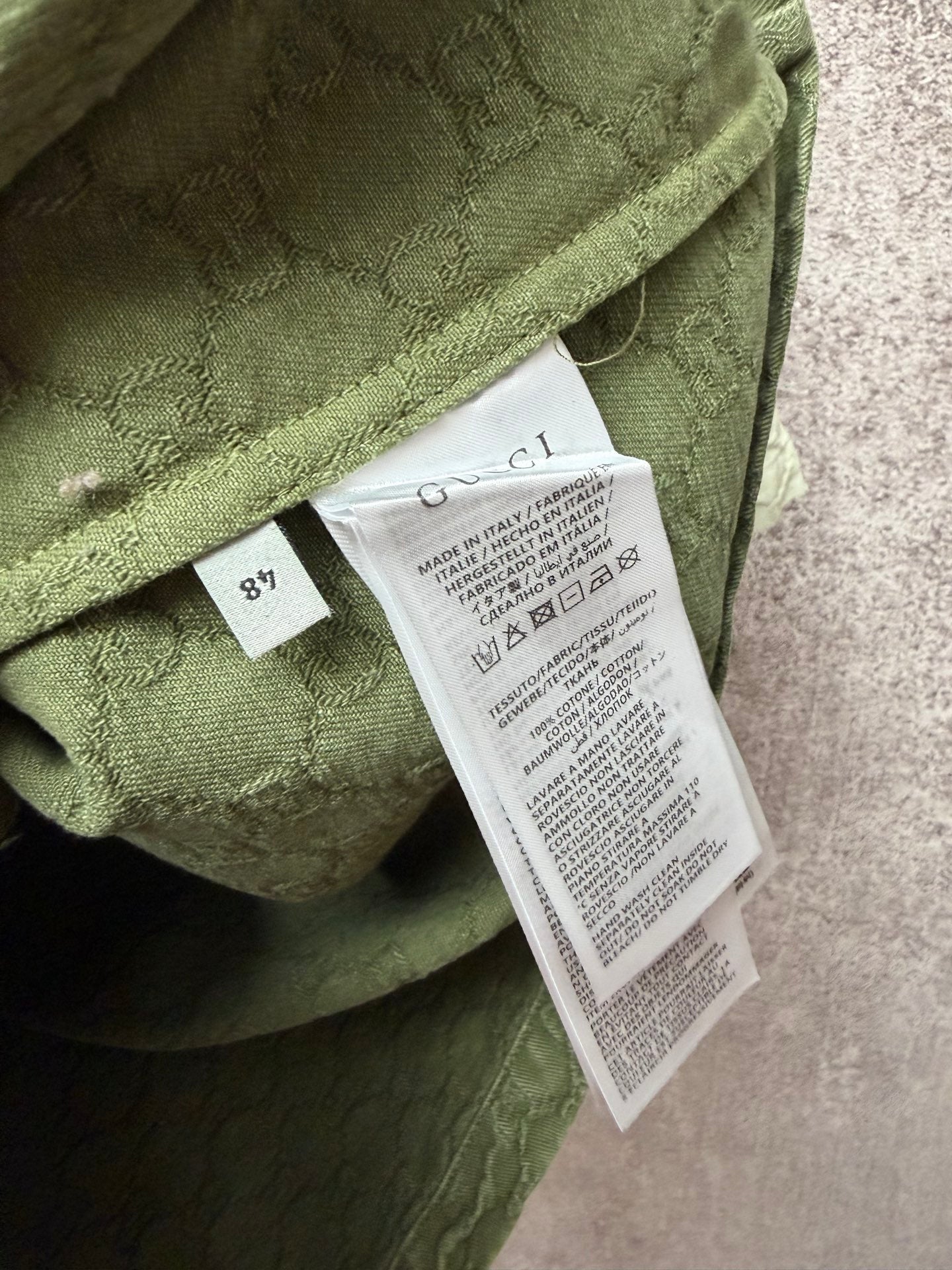 Gucci short-sleeve shirt care label tag on olive green textured fabric