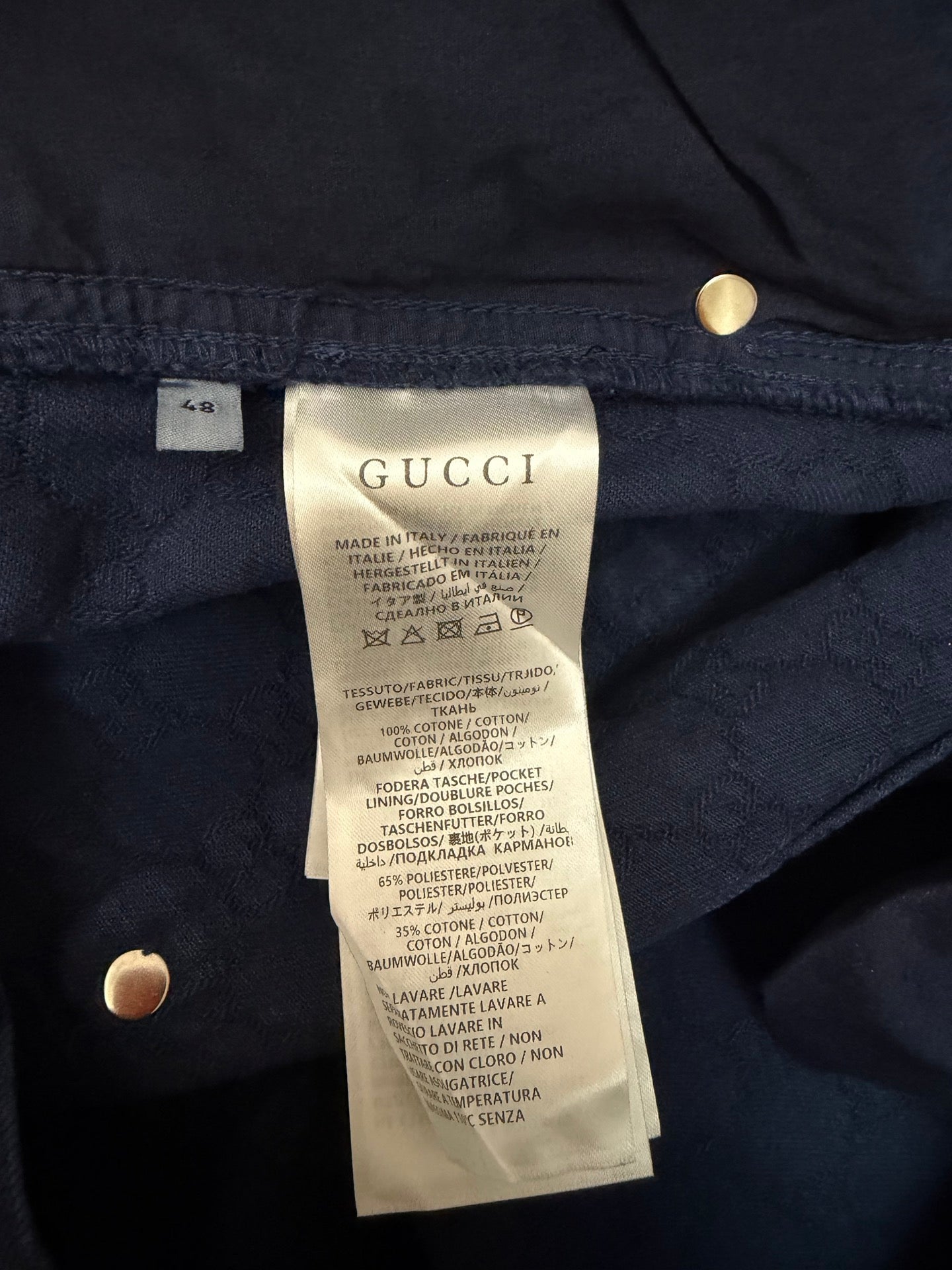 Gucci size and fabric label on navy shorts, close-up of inner tag and buttons