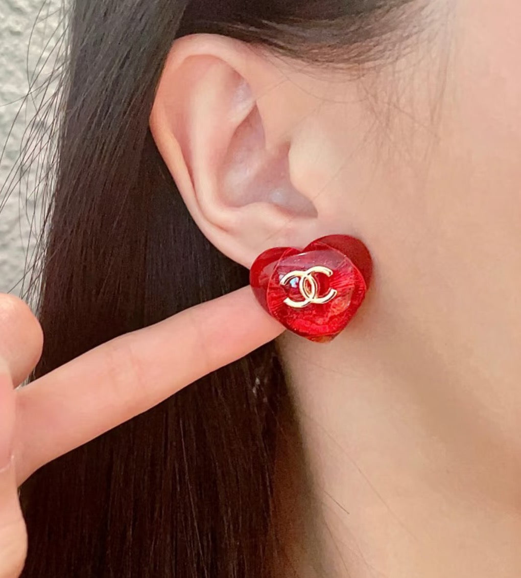 Red Chanel CC stud earring on ear, round glossy face with gold logo