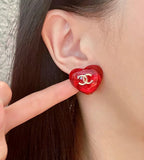 Red Chanel CC stud earring on ear, round glossy face with gold logo