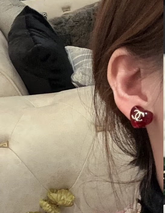 Red Chanel CC stud earring worn on ear with glossy round design