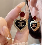 Heart dangle earrings with red enamel tops and black CC heart charms on gold posts