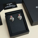 Pair of heart dangle earrings with red enamel tops, gold-tone CC logo, and black hearts