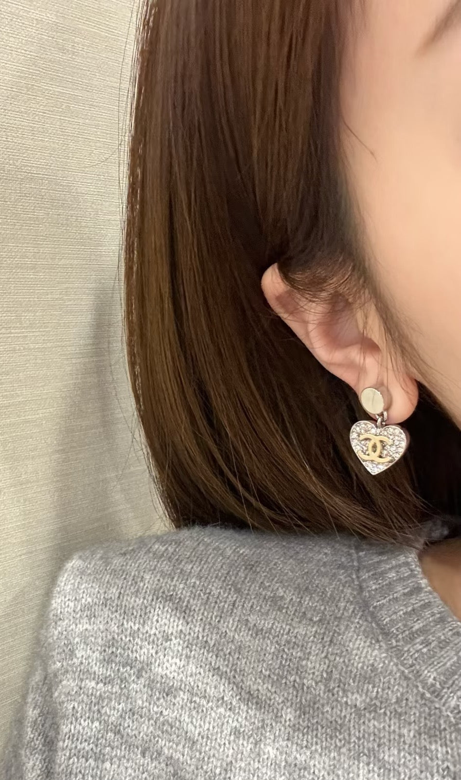 Gold and silver heart earrings with CC logo dangle on earlobe