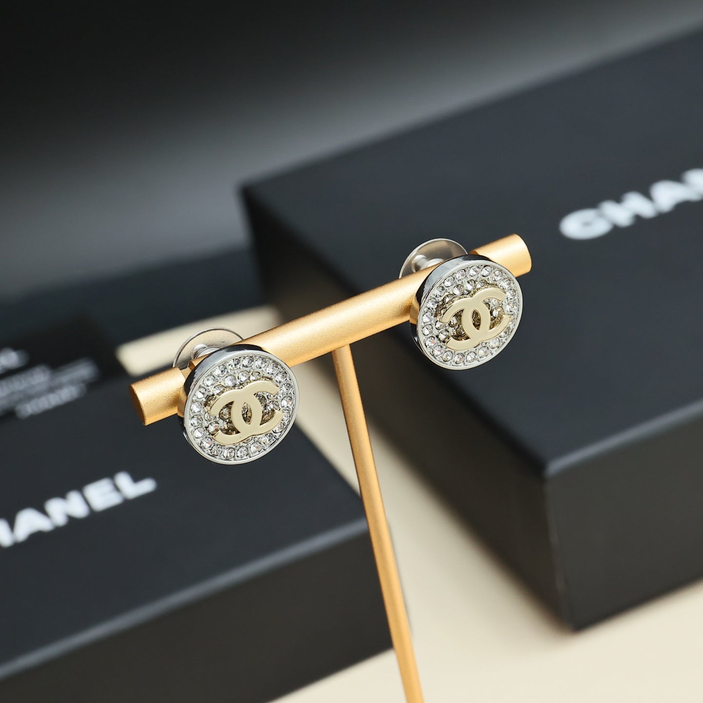CC stud earrings, round pavé border silver-tone with gold CC center on stand