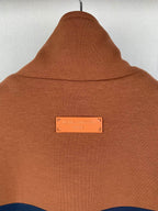 Brown jacket hood and neck area with a small rectangular logo label at center