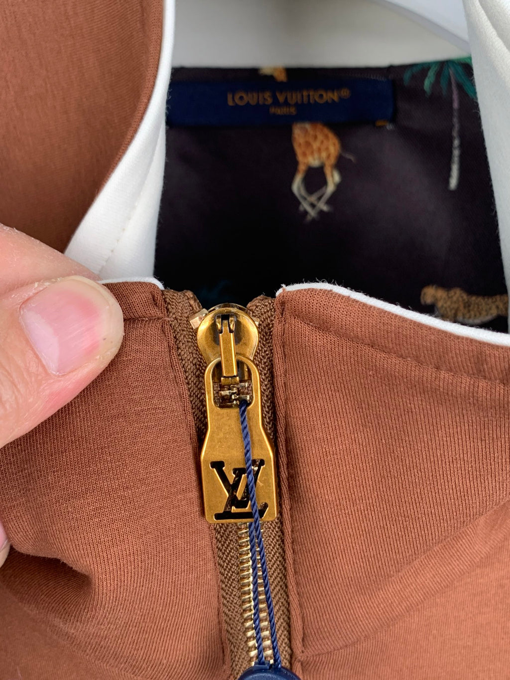 Brown jacket zipper close-up with Louis Vuitton V emblem and gold hardware pull