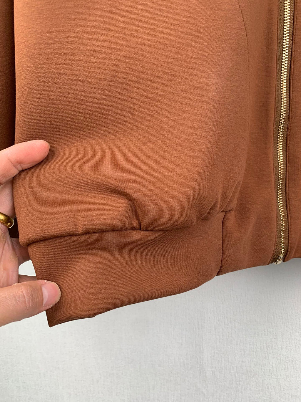 Brown jacket lower cuff with gathered elastic seam; zipper edge visible at side