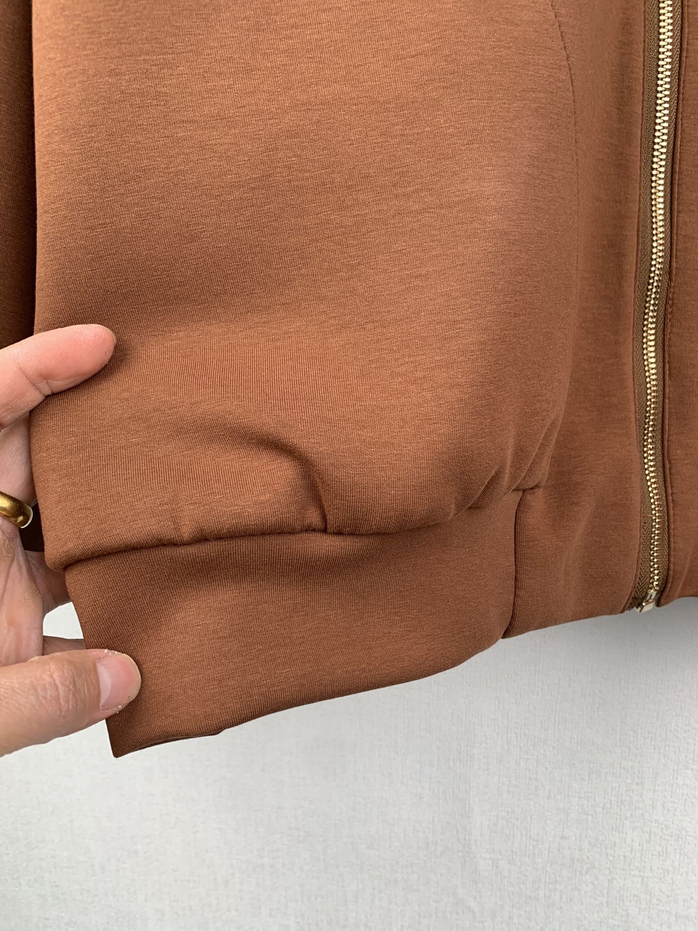 Brown jacket lower cuff with gathered elastic seam; zipper edge visible at side
