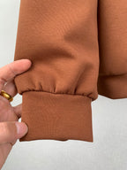 Brown jacket sleeve cuff with gathered seam detail and elastic hem